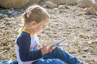 Young girl enjoying a peaceful moment by the lake while immersed in a captivating book