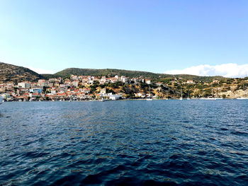 Scenic view of sea by townscape against sky