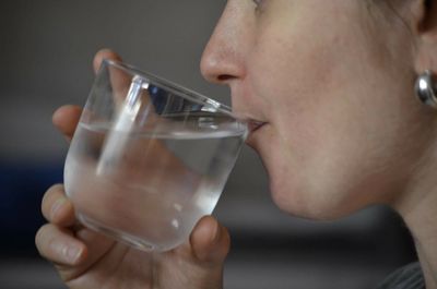 Midsection of woman drinking water at home