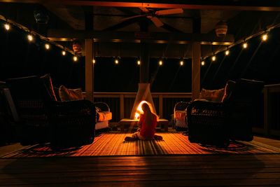 Full length of man sitting on wooden floor at night