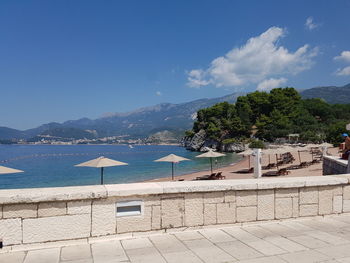 Scenic view of swimming pool by sea against blue sky