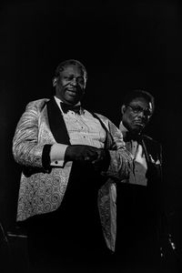 Portrait of man standing against black background