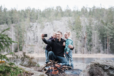 Father taking pictures with his kids whilst enjoying a campfire