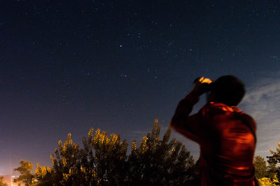 Rear view of man photographing against sky at night