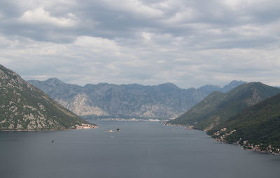 Scenic view of sea by mountains against sky