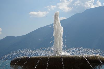 Water splashing on mountain against sky