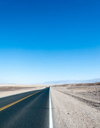 Road amidst landscape against clear blue sky