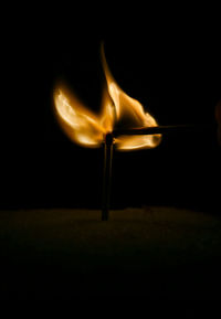 Close-up of burning candle against black background