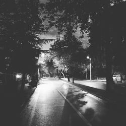 Empty road along trees and against sky