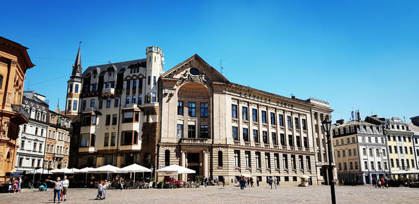 Buildings in city against clear blue sky