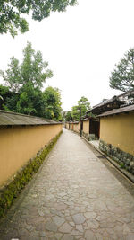 Walkway amidst trees against clear sky