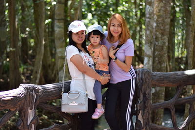 Portrait of sisters with daughter in forest