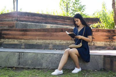 Full length of woman sitting on mobile phone