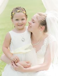 Close-up of happy woman with baby girl standing against wall