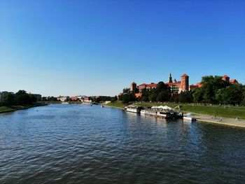 Scenic view of river by buildings against clear sky