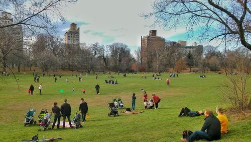 People relaxing on grassy field in park