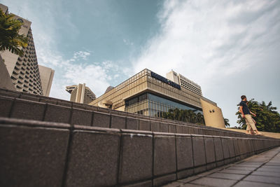 Low angle view of man standing by railing against buildings