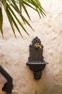 Old ornate brass water tap and basin fixed on a white plastered wall in a garden