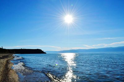Scenic view of sea against blue sky on sunny day