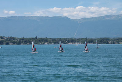 People in sea against mountains