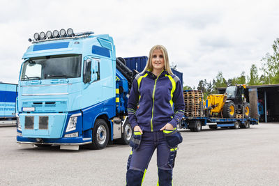 Blond female truck driver standing next to truck