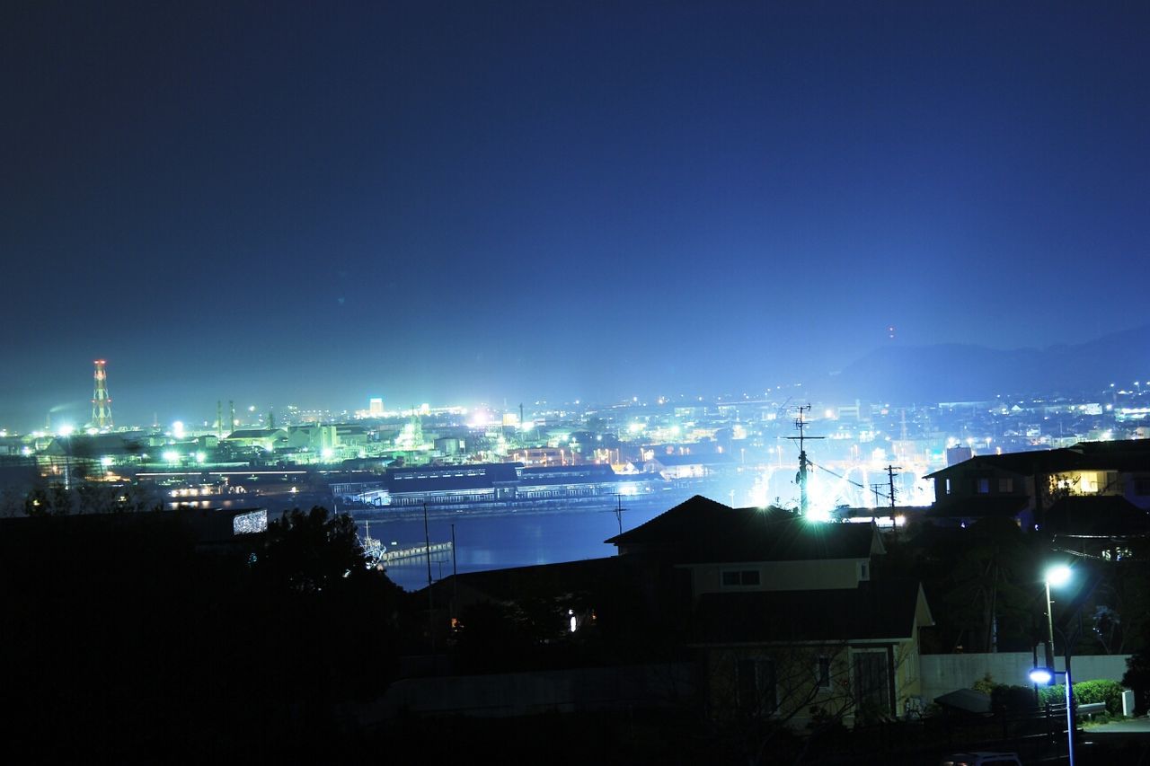 illuminated, night, building exterior, architecture, built structure, city, cityscape, copy space, clear sky, residential district, residential building, residential structure, sky, blue, development, dark, city life, crowded, high angle view, outdoors