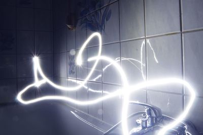 Low angle view of light trails against wall at night