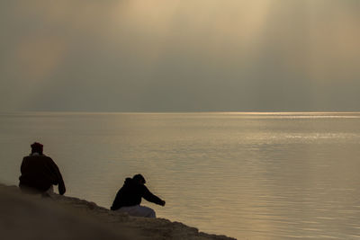 Silhouette people on beach against sky during sunset
