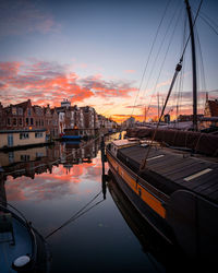 Sailboats moored at harbor against sky during sunset