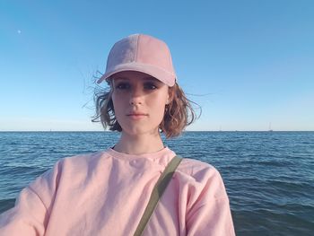 Young woman wearing cap against sea