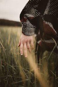 Midsection of woman on field against sky