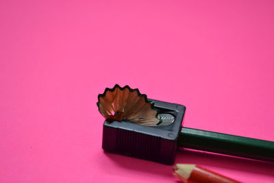 Close-up of colored pencils on table against pink background