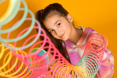 Teen girl play rainbow slinky toy on color background