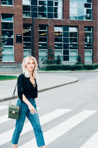 Portrait of smiling woman standing against building in city