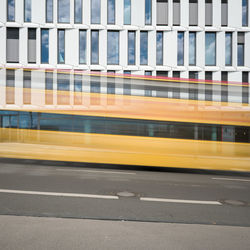 Blurred motion of bus on road against buildings