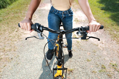 Low section of woman riding bicycle on footpath