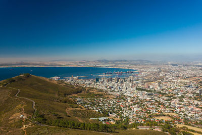 High angle view of townscape by sea against blue sky