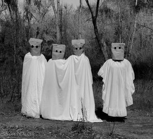 People standing on field by trees in forest