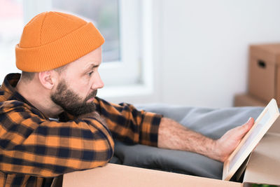 Mature man unpacking things from boxes while moving in new apartment.