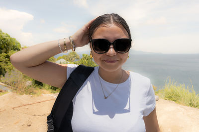Portrait of young woman standing against sky