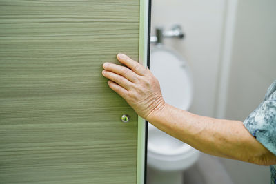 Cropped hand of woman entering bathroom at home