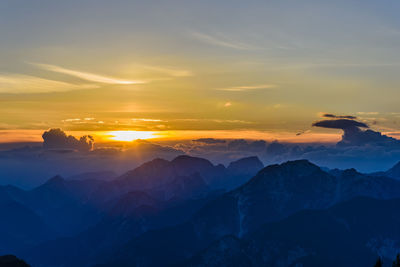 Scenic view of mountains against dramatic sky during sunset