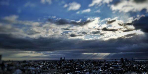 Aerial view of city against cloudy sky