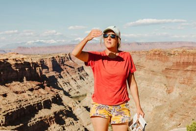 Female hiker bocks sun with her hand to measure sunset time in utah