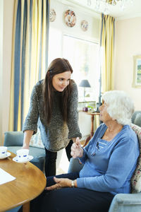 Young woman serving coffee to grandmother at home