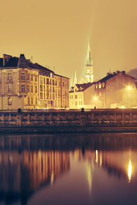 Illuminated church reflecting on river in city at night