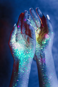 Close-up of woman hand illuminated multi colored light painting