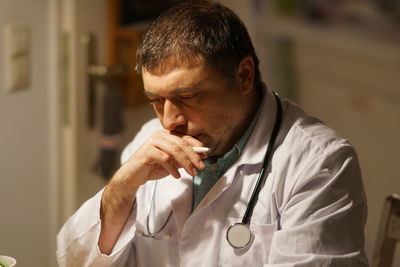 Thoughtful mature doctor with pen working in hospital