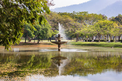 Fountain in lake against trees