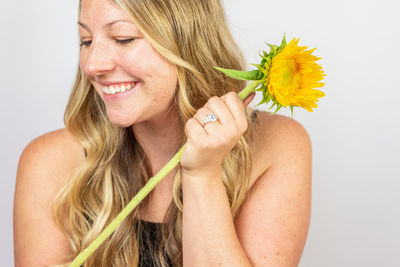 Portrait of a smiling young woman holding yellow flower
